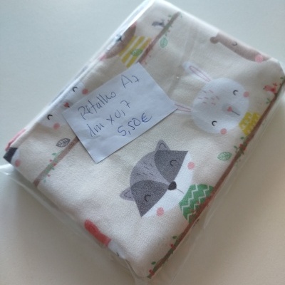 tecido estampado com animais infantis embalado em plástico com etiqueta manuscrita