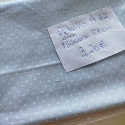 Tecido azul claro com pontos brancos e etiqueta manuscrita com medidas e preço