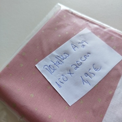 Toalha de algodão rosa com pequenos pontos dourados, embalado em plástico com etiqueta manuscrita