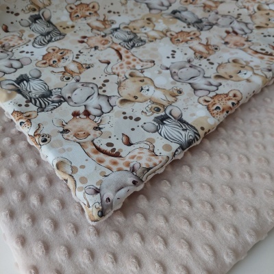 Manta dupla com tecido de girafas e outros animais bebés em tons neutros e tecido bege claro com textura de bolinhas.