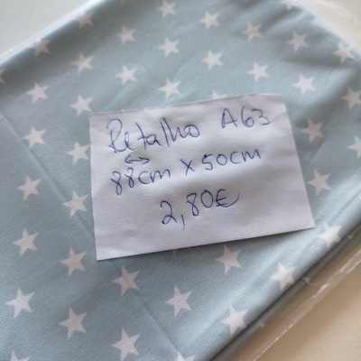 Retalho de tecido azul claro com estrelas brancas, embalagem transparente e etiqueta com texto manuscrito.
