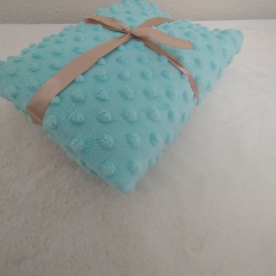 Manta azul turquesa com textura de bolinhas e fita castanha clara