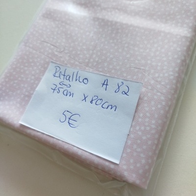 Pacote de retalho de tecido cor-de-rosa com pontos brancos e etiqueta escrita à mão