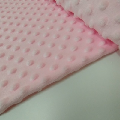 Tecido rosa claro com textura de relevos arredondados sobre superfície branca.