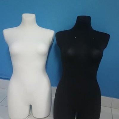 Dois manequins femininos preto e branco lado a lado contra parede azul