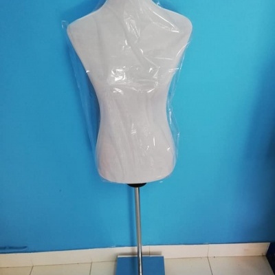 Manequim branco com base metálica contra parede azul