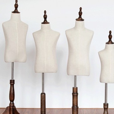 Quatro manequins femininos de diferentes tamanhos com bases em madeira escura