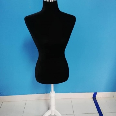 Manequim de costura preto com base branca em frente a parede azul