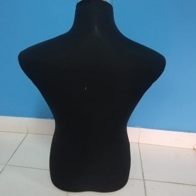 Manequim torso masculino preto com topo metálico frente a parede azul