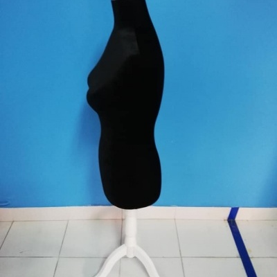 Manequim preto em tripé branco numa sala de parede azul