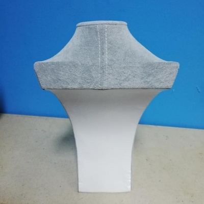 Expositor de bijuteria cinzento e branco em balcão contra parede azul