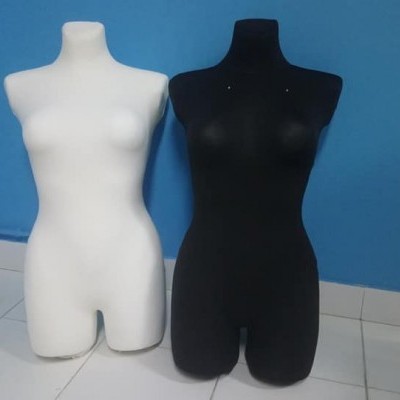 Dois manequins femininos, um branco e um preto, sobre piso branco e parede azul.