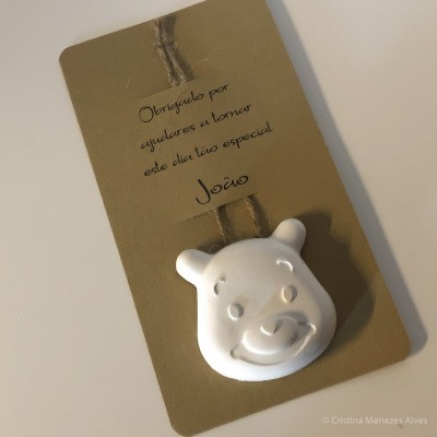 Etiqueta castanha com cordel e enfeite branco de cabeça de urso