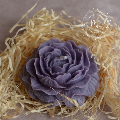 Vela lilás em forma de flor rodeada por palha seca