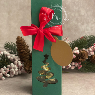 Caixa verde decorada com laço vermelho e recorte de árvore de Natal dourada