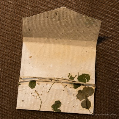 Envelope artesanal branco com folhas prensadas e corda amarrada