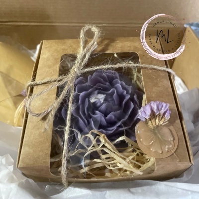 Caixa de presente com vela em forma de flor roxa e decoração seca
