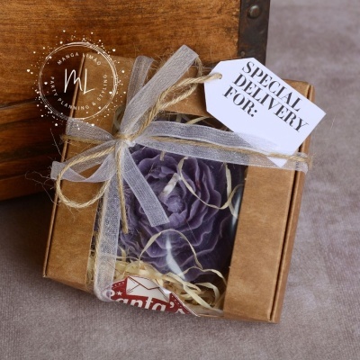 Caixa de presente com flor roxa decorativa, fita cinza e etiqueta 'SPECIAL DELIVERY FOR:'