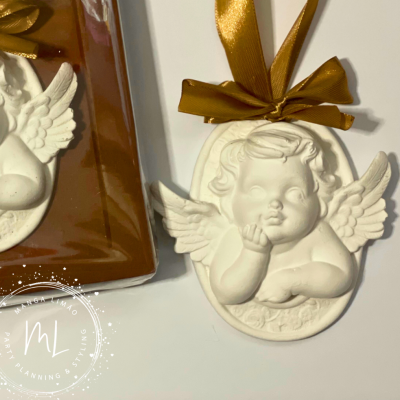Adornos em forma de anjo branco com laço dourado em fundo branco