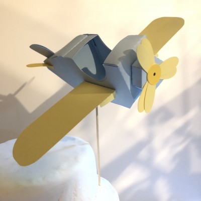 Modelo de avião cinza e amarelo em cardboard montado numa vareta