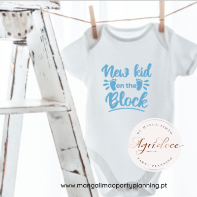 Body branco para bebé com texto azul 'New kid on the Block' pendurado ao lado de escada branca envelhecida