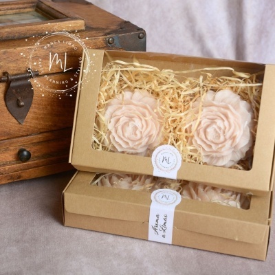 Caixas com sabões florais rosa dentro, junto a baú de madeira escura