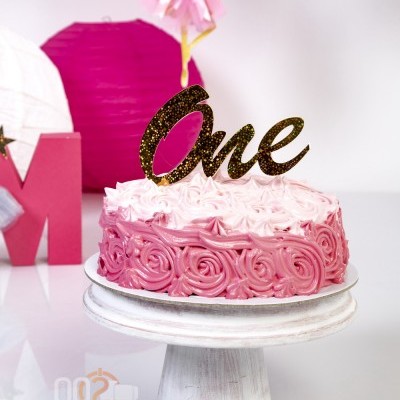 Bolo de aniversário rosa com topper dourado 'One' em suporte branco