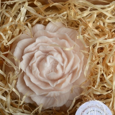 Sabonete em forma de flor cor de rosa claro sobre palha amarela numa embalagem