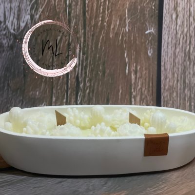 Vela artesanal em taça oval, com pequenas flores em tons de branco