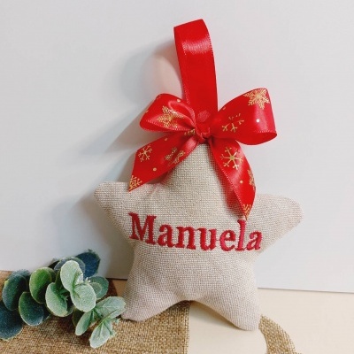 Estrela decorativa em tecido bege com nome Manuela e fita vermelha com flocos dourados