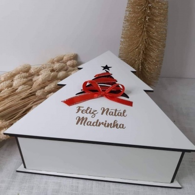 Caixa branca em forma de árvore de Natal com decorações vermelhas e pretas e texto 'Feliz Natal Madrinha'