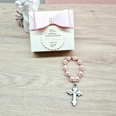Caixa branca com laço rosa e terço com contas rosa e cruz com gravação