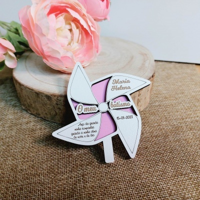 Marcador de batismo em forma de moinho de vento em madeira branca e rosa com texto, flores e base de madeira