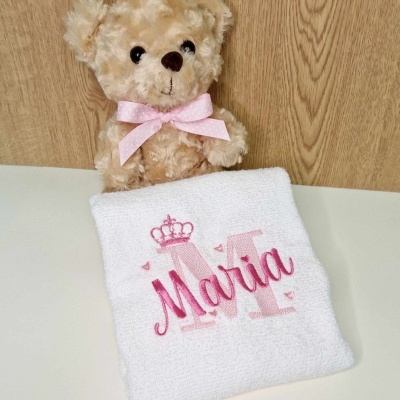 Ursinho de peluche castanho claro com laço rosa claro e toalha branca bordada com nome Maria