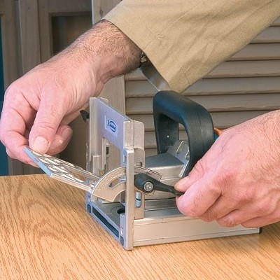 ferramenta elétrica de corte manual sobre mesa de madeira com mãos ajustando peça metálica