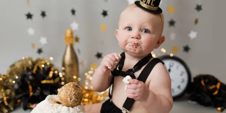 Bebé com chapéu e suspensórios a comer bolo em ambiente festivo com decoração de estrelas