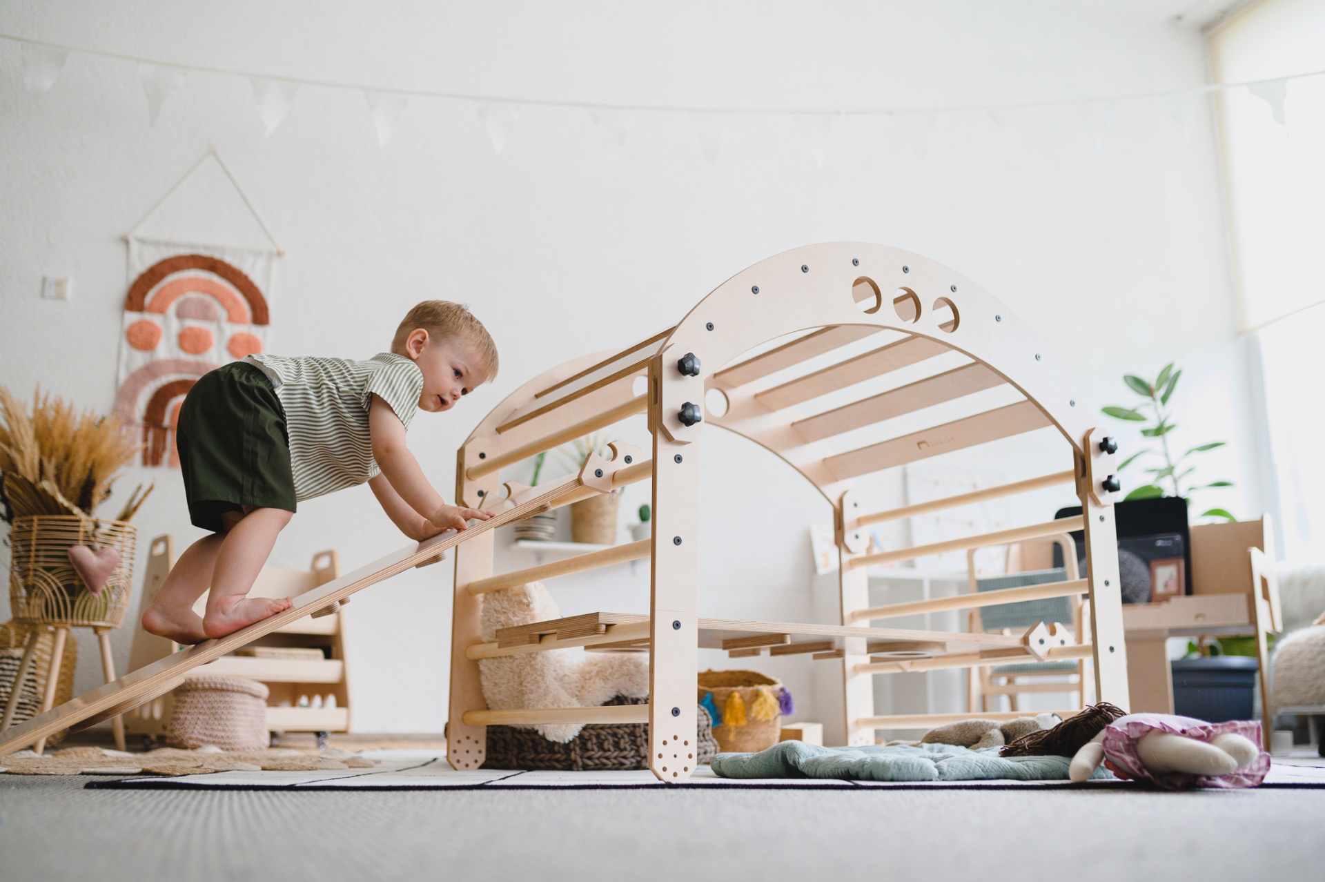 Criança a brincar numa estrutura de madeira clara num quarto