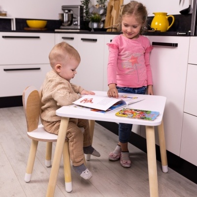 Mesa e cadeira infantil brancas com pernas em madeira clara e crianças numa cozinha moderna