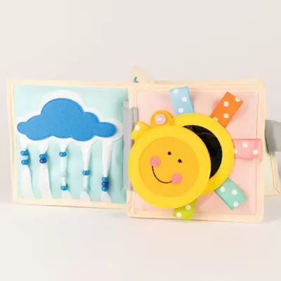 Livro de tecido infantil com nuvem e sol coloridos e fitas de diferentes cores