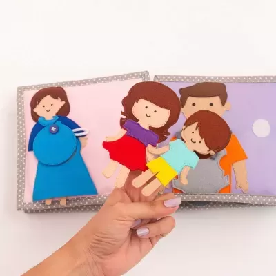 Livro macio de tecido com figuras em feltro coloridas representando pessoas