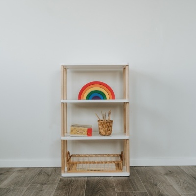 Estante pequena de madeira clara com objetos decorativos coloridos
