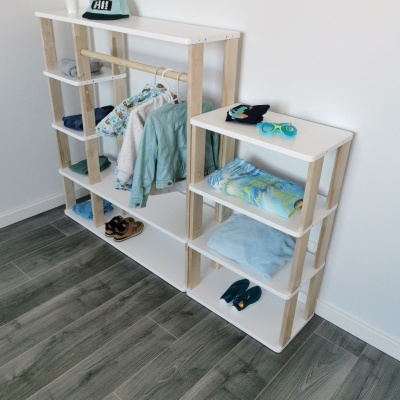 Estantes brancas e madeira com roupas e acessórios organizados.