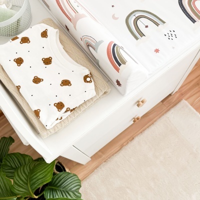 Roupa de bebé com padrão de ursinhos e almofada para troca com padrão de arco-íris