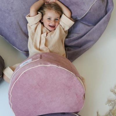 Criança deitada sobre almofadas roxas e rosa