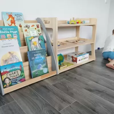 Estante com livros infantis e brinquedos, criança a brincar no chão