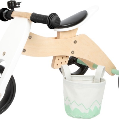 Bicicleta de equilíbrio infantil em madeira clara com rodas e guiador preto, e cesto branco e verde.