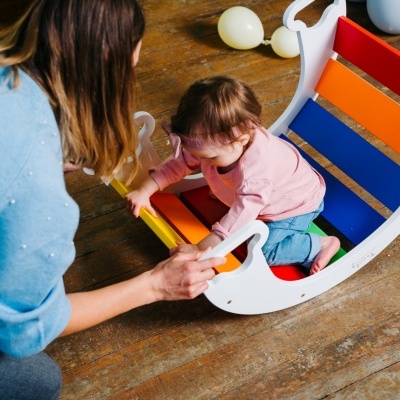 Cadeira de madeira colorida com criança sentada e adulto ao lado