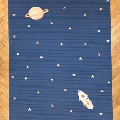 Tapete azul com estrelas, planeta e foguete sobre chão de madeira