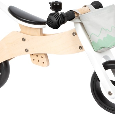 Bicicleta infantil de equilíbrio em madeira, rodas pretas e saco branco com padrão verde