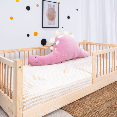 Cama de criança em madeira clara com peluche rosa e decoração de parede